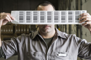 A warehouse worker holding up a sheet of bar code shipping lables in a distribution warehouse.