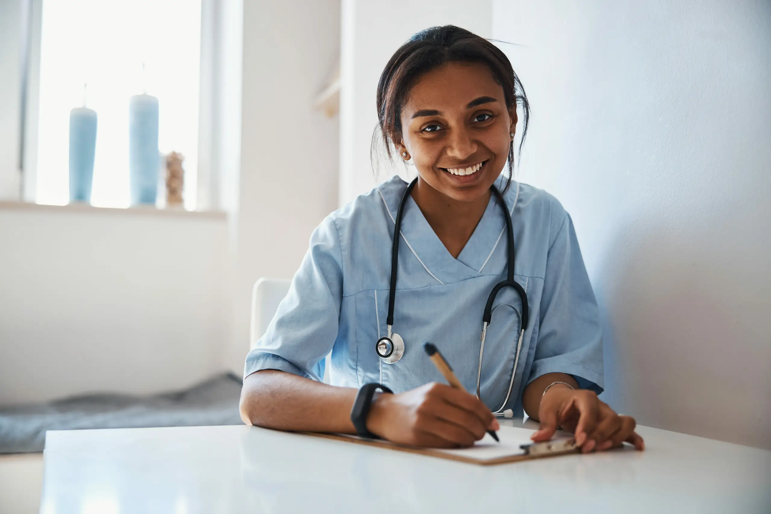 Cheerful female doctor doing paperwork in a clinic, highlighting healthcare communication, compliance management systems, integrated healthcare, and medical inventory management to reduce paperwork and simplify your medical device company.