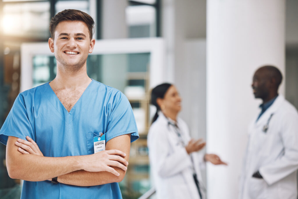 Portrait of a male nurse with his team in the background in the hospital, highlighting care coordination, healthcare communication, patient management software, and integrated healthcare.