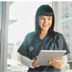 Medical researcher and nurse with a tablet in a clinic, highlighting healthcare analytics, care coordination, integrated healthcare, and patient management software.